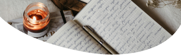Image of an open book with handwriting and a pen lying along the center fold