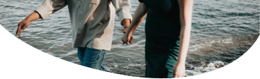 Two people holding hands walking on the sea shore