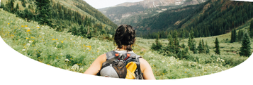 the back of a female wearing a yellow backpack, hiking in mountains