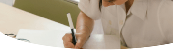 image of a female working at a desk and writing in a book