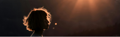 silhouette profile image of a female with sunlight glowing behind her and lighting her hair