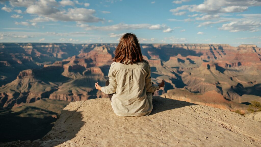 picture of lady sitting on the edge of a canyon looking peaceful